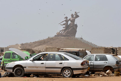 Un taller de reparación de automóviles, ante el Monumento al Renacimiento Africano, en Dakar.