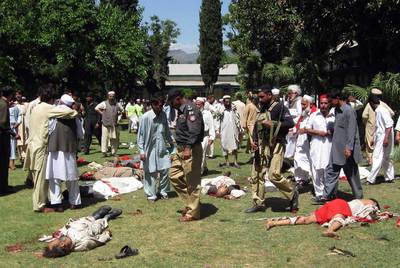 Policías paquistaníes y seguidores del partido Awami caminan entre los cuerpos de las víctimas de un ataque suicida en Timergarah.