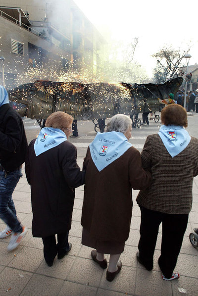 Tres mujeres, con sus pañuelos con el escudo y los colores de La Canonja, contemplando el  correfoc .