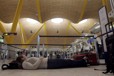 Una viajera que no pudo volar descansa en el suelo de la terminal 4 del aeropuerto de Barajas.