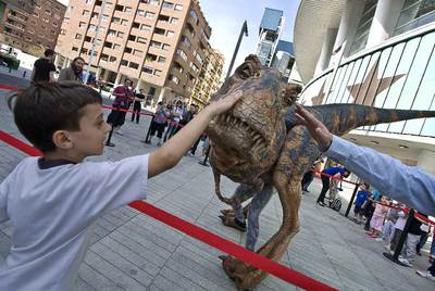 Un niño toca una de las maquetas utilizadas en el espectáculo  Caminando entre dinosaurios,  delante del Palacio de Deportes.