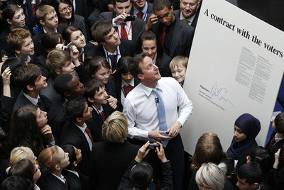 David Cameron, junto a un cartel con su firma donde se lee: 