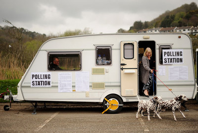 Una mujer sale con sus perros de una caravana convertida en colegio electoral en Cornualles, al sureste de Inglaterra.