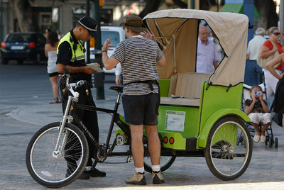 Un agente de Málaga revisa la documentación del conductor de una  bicitaxi  el pasado verano.
