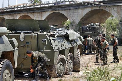 Un soldado trabaja junto al vehículo siniestrado, tras ser levantado por una grúa, junto al puente por el que se precipitó.