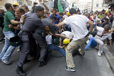 Varios manifestantes forcejean con la policía durante la protesta de ayer en L'Aquila.