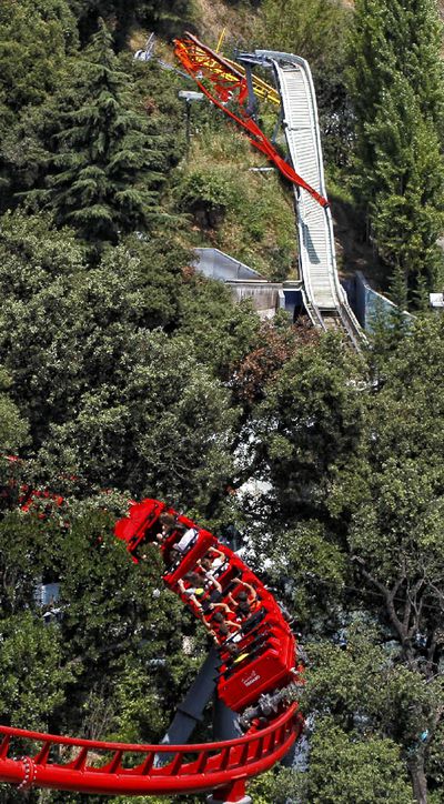 Pasajeros de la montaña rusa pasan frente a 'El Péndulo'.