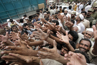 Paquistaníes afectados por las inundaciones tratan de conseguir alimentos durante un reparto de ayuda.