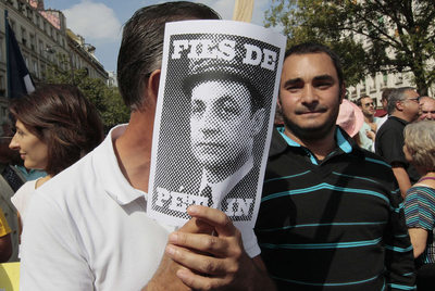 Un manifestante muestra una imagen de Sarkozy, caricaturizado como  hijo de Pétain. 