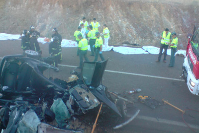 Guardias civiles, bomberos y personal sanitario, junto al amasijo de hierros en que quedaron los vehículos. Detrás, varios de los cadáveres.