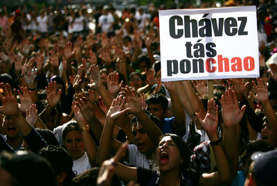 Estudiantes universitarios se manifiestan en contra de Chávez, al que la pancarta define como 