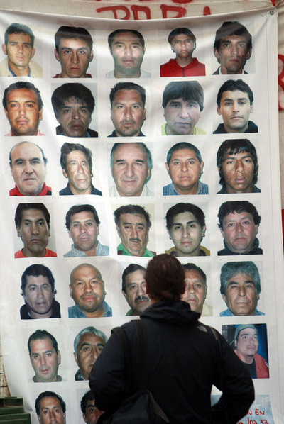 Un hombre observa un cartel con los rostros de los 33 mineros atrapados en la mina San José.