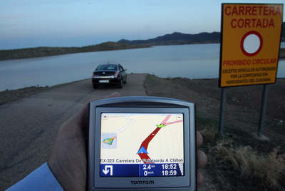 Un GPS marca la ruta inundada por el pantano. La orilla aparece muy cerca del cartel que prohíbe el paso. En ese navegador, una flecha verde y otra blanca aconsejan darse la vuelta. En la otra imagen, Daniel Muñoz y José Luis Salgado, muestran dónde cayó el coche.