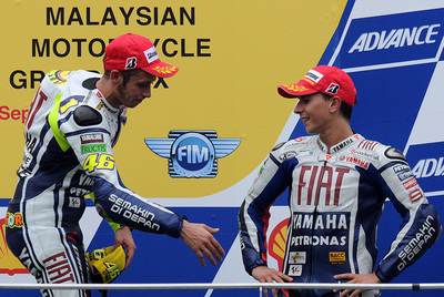 Rossi busca el saludo de Lorenzo en el podio del circuito de Sepang.