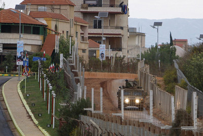 Un  jeep  israelí patrulla en la frontera con Líbano a la altura de Kfar Kila, donde se ven carteles de Ahmadineyad.