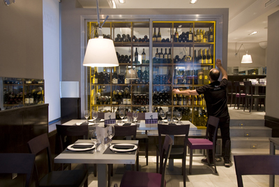 Comedor del restaurante Arzábal, en Madrid. Abajo, plato de patata a la importancia con cigala albardada en ibérico.