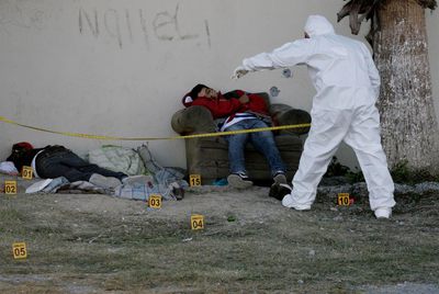 Un forense de la policía mexicana examina los cuerpos de dos hombres asesinados por el  narco  en las afueras de Monterrey.