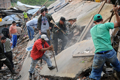 Soldados y habitantes de un barrio de Medellín levantan los escombros para localizar a víctimas del alud.