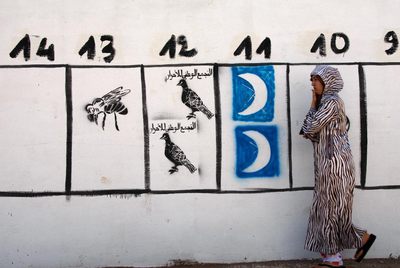 Una mujer camina ante dibujos de propaganda electoral en una calle de Rabat.