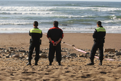 Un   ertzaina,   junto con dos policías locales, durante un operativo en una playa vizcaína.