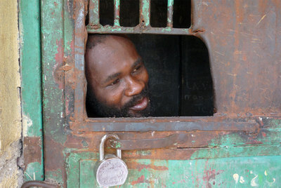 Un enfermo se asoma por la ventanilla de una de las celdas de castigo de un hospital psiquiátrico en Puerto Príncipe.
