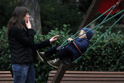 Una mujer fuma muy cerca de un niño en una zona infantil del parque del Retiro, ayer, en Madrid.