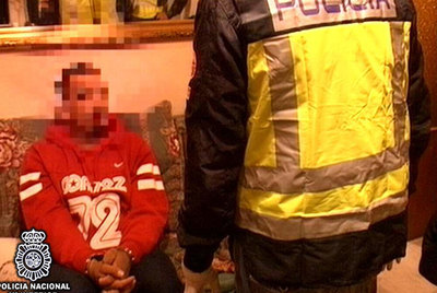 Un policía vigila a un miembro de los Dominican Don't Play detenido.