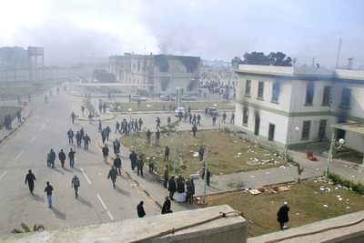 Grupos de manifestantes se desplazan por la ciudad de Bengasi entre el humo procedente de choques armados y de edificios quemados.