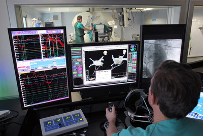 El cardiólogo (sentado) maneja la sonda que se mueve en el corazón del paciente (al fondo) en el hospital de La Paz (Madrid).