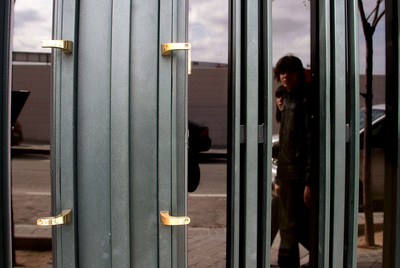 Una pareja pasa frente a una de las puertas de la calle de Mirasierra donde han robado uno de los tiradores.