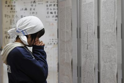 Una evacuada busca a sus amigos en un listado de un refugio.