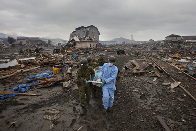Soldados y un voluntario transportan el cadáver de un habitante de Ciudad de Kesennuma.