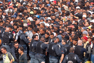 La policía italiana intenta controlar a inmigrantes de Túnez que esperan en Lampedusa el reparto de comida.
