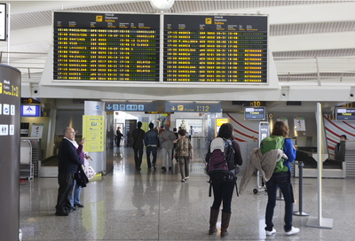 Dos jóvenes con mochilas observan una pantala informativa en el aeropuerto de Loiu.