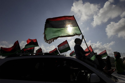 Un joven, sentado sobre el parabrisas de un coche, hace ondear la bandera libia durante una manifestación en Bengasi, el 31 de marzo de 2011.