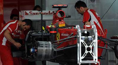 Dos operarios revisan ayer, en los talleres de Sepang, el bólido de Fernando Alonso.