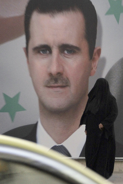 Una mujer con  niqab , ante un cartel de El Asad en Damasco.