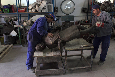 Dos operarios mueven la estatua  Tras Julia. 