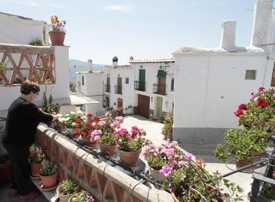 Una vecina de Yegen (Granada) riega las macetas de su tinao, soportal típicamente alpujarreño, sobre la calle de Gerald Brenan, el escritor que vivió cuatro años en el pueblo.