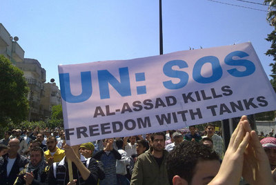 Manifestantes muestran una pancarta en la que piden ayuda a la ONU y denuncian la represión de El Asad.