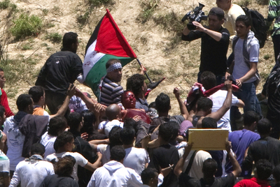 Refugiados palestinos evacuan a un herido durante los disturbios en la línea que separa territorio sirio del ocupado por Israel en el Golán.