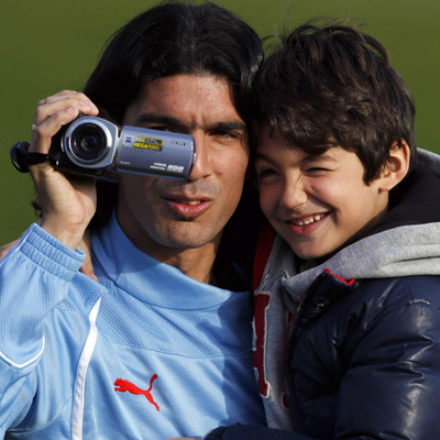 Abreu, con su hijo Diego al hombro, graba un entrenamiento de Uruguay.