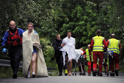 Personal de los equipos de emergencia acompaña a algunos supervivientes de la matanza en el campamento, ayer en la isla de Utoya.