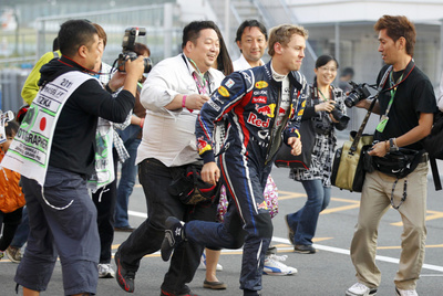 Vettel escapa a la carrera de fotógrafos y aficionados ayer en Suzuka.