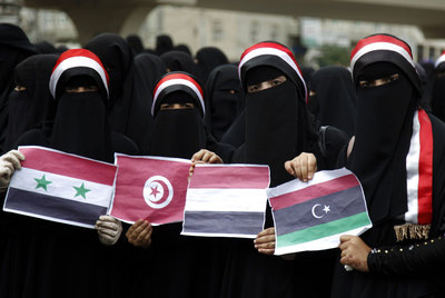 Unas mujeres muestran las banderas de Siria, túnez, Yemen y Libia en una manifestación.