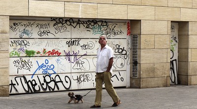 Un hombre pasa ante la entrada cerrada del aparcamiento de Velluters en Valencia.