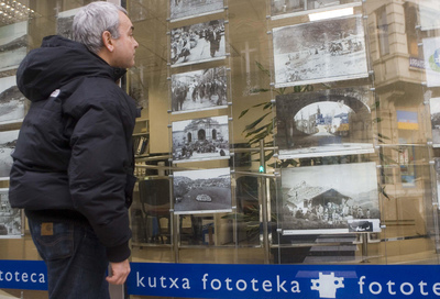 Un hombre contempla varias fotos antiguas expuestas en el escaparate de la fonoteca de Kutxa.