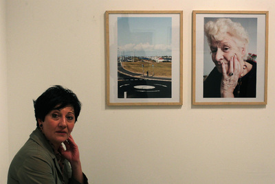 La fotógrafa Ione Saizar posa ante dos de las instantáneas de  Please take all the baggage with you .