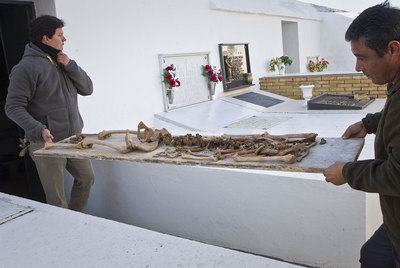 Dos técnicos trasladan los restos de uno de los cadáveres hallados en la fosa de Gerena en la que fueron enterradas  Las   17 rosas. 