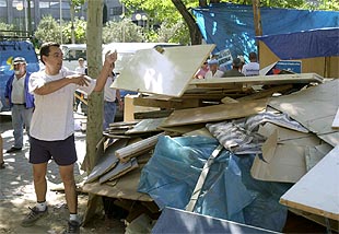 Un trabajador de Sintel arroja una tabla a uno de los contenedores, durante los trabajos de limpieza de la Castellana.